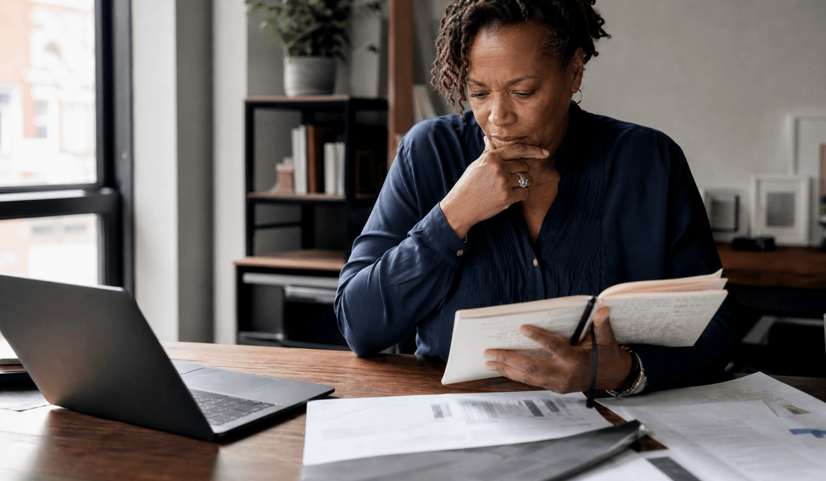 Thoughtful professional woman reviewing notes at a desk, representing judgment, story, and accountable action in an AI-shaped consulting market.